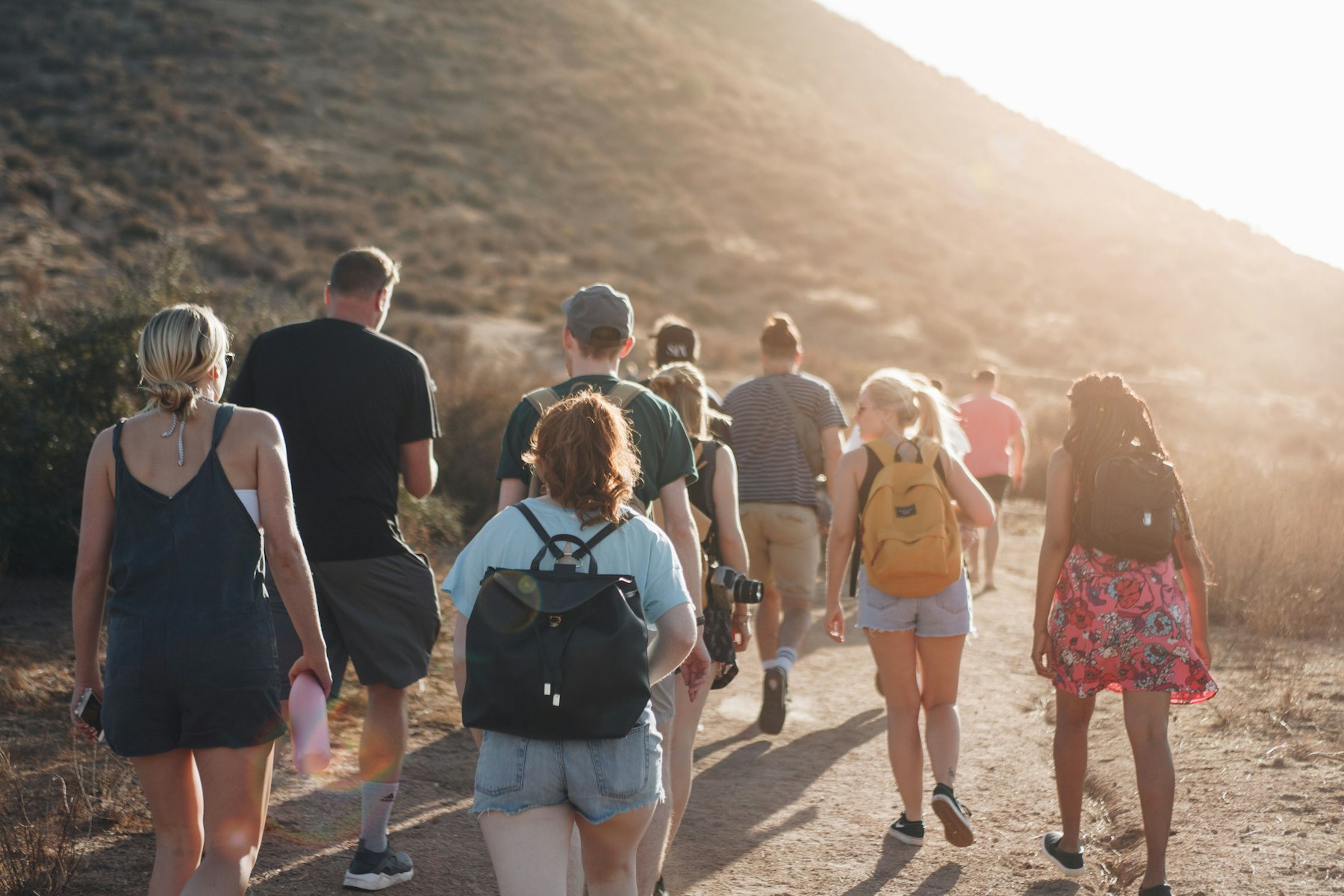 A group of people hiking up a trail together at sunrise