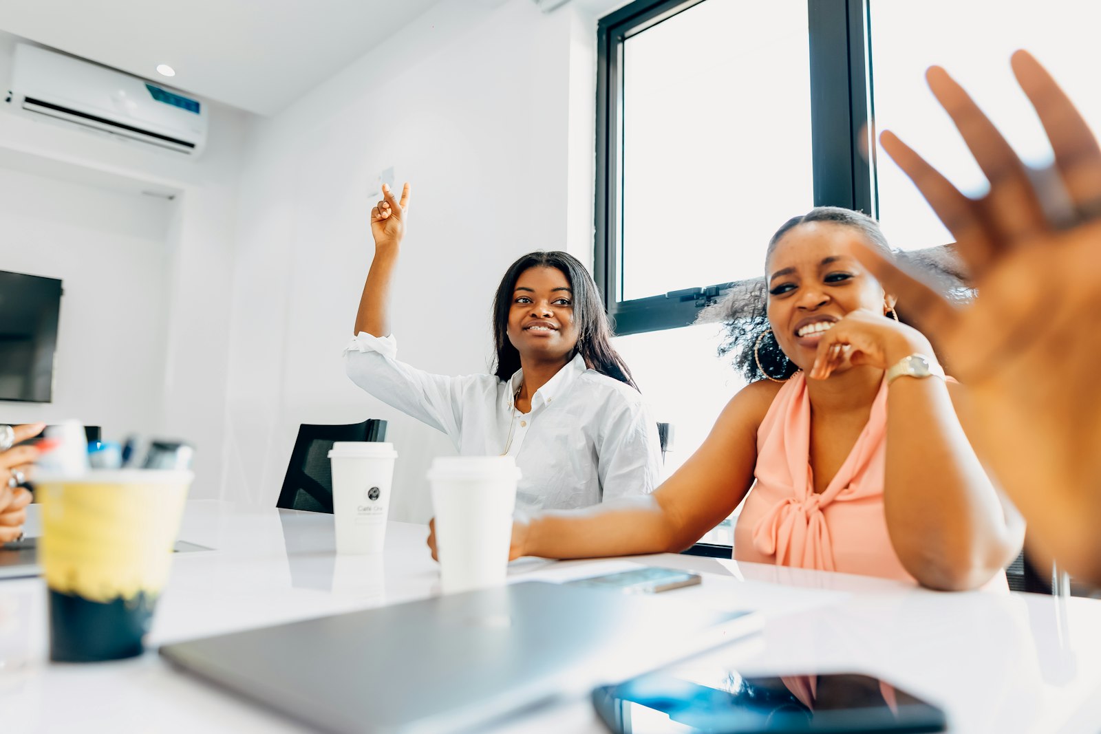 Two women sharing ideas and laughing around a meeting table